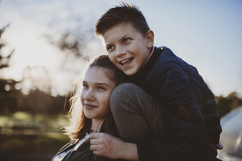 a sister and brother portrait smiling while looking away during a golden hour fall family session by Bella Luna Photography in Leesburg, VA