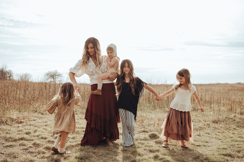 a mom and her 4 daughters are twirling and dancing on grass field captured by Bella Luna Photography