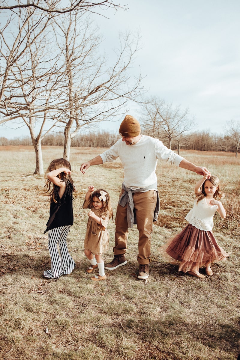 a dad is playing with his daughters during a family photoshoot in leesburg by bella luna photography