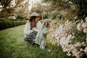mom and daughter smell flowers during a family session at a perfect location in Leesburg, VA