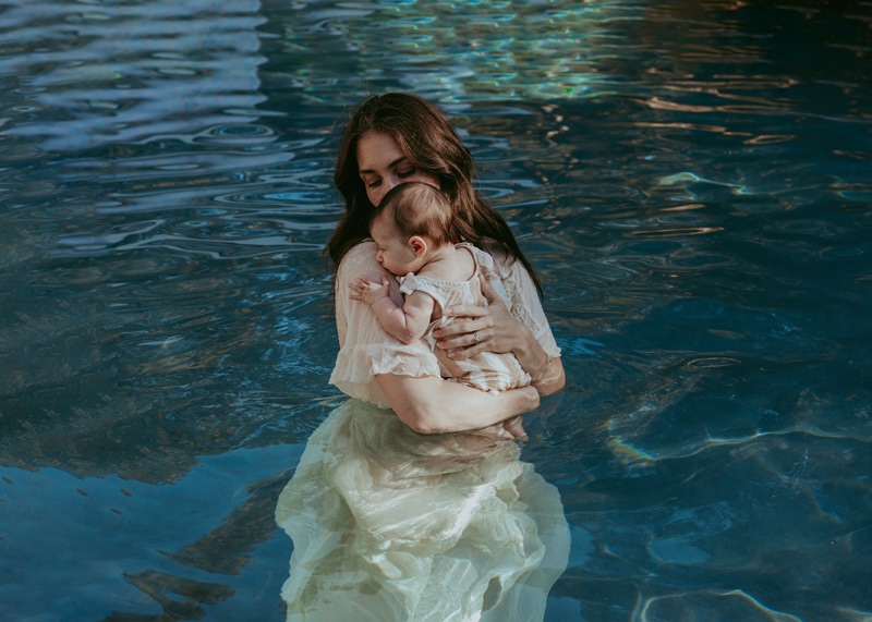 Mom holding her baby in the pool during a family photo session in Loudoun County by Bella Luna Photography