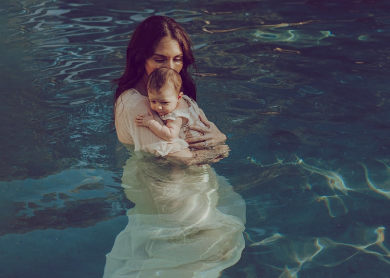 Mom holding her baby in the pool during a family photo session in Loudoun County by Bella Luna Photography