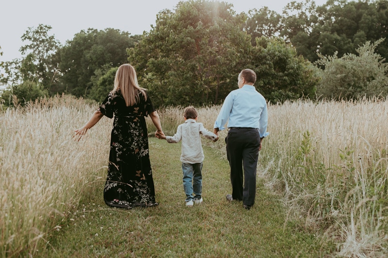 A mom, son, and dad holding their hands and walking away during a golden hour family session in Leesburg, VA by Bella Luna Photography