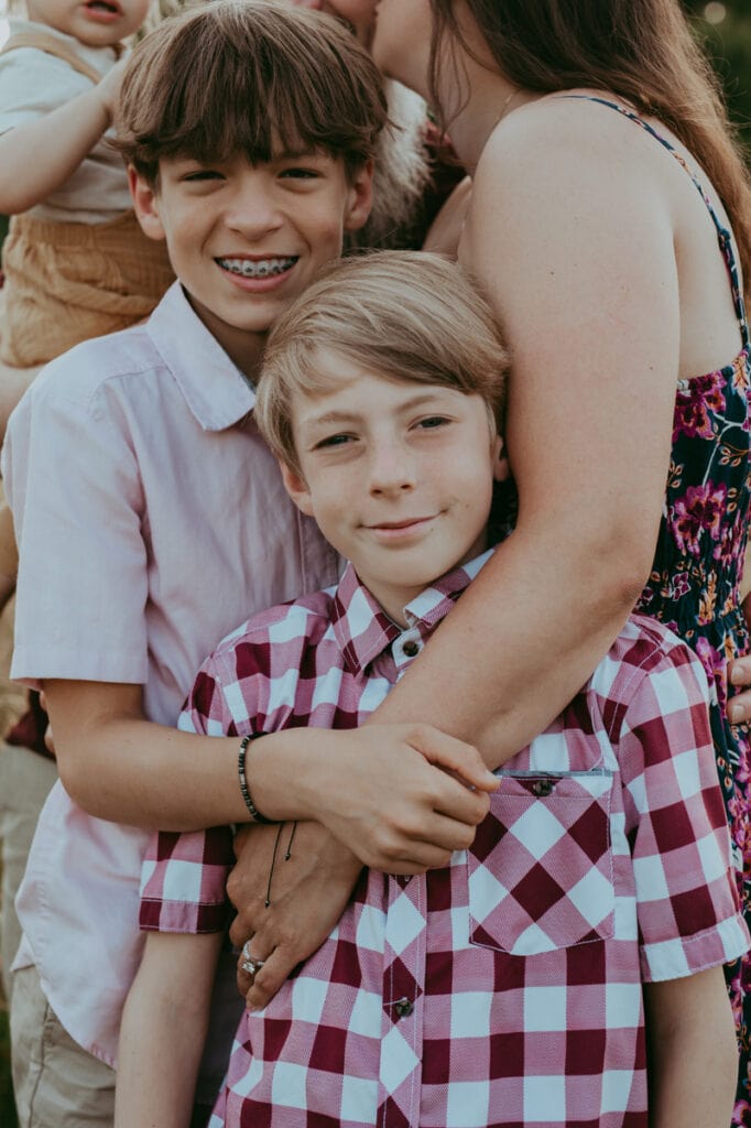 two brothers looking a the camera while hugging mom's arm during a family photoshoot by Bella Luna Photography