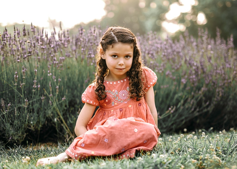 a girl in a red dress posing next to lavender during an outside summer family session in Loudoun County by Bella Luna Photography