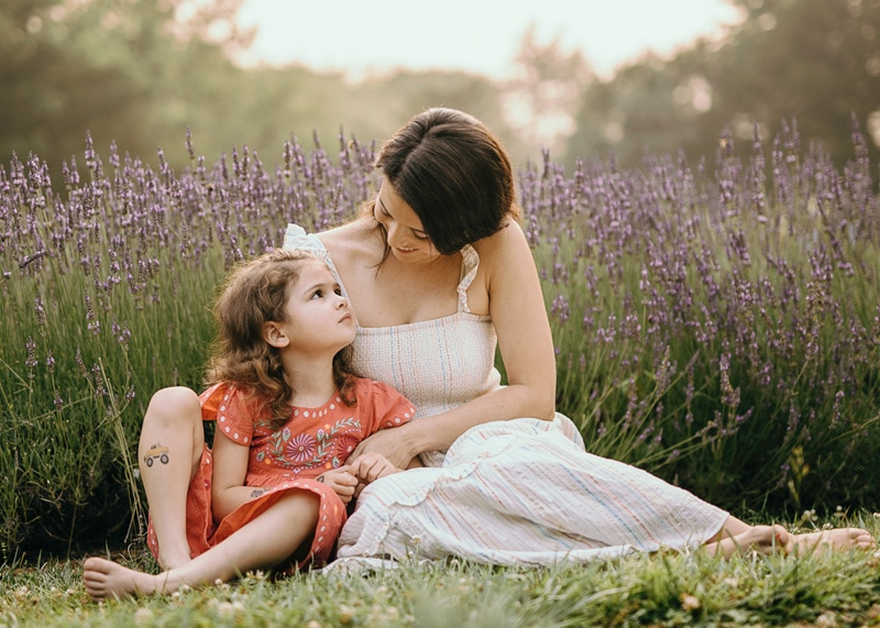 a daughter in red dress looking up at mom during a summer family session at lavender farm in Northern VA by Bella Luna Photography