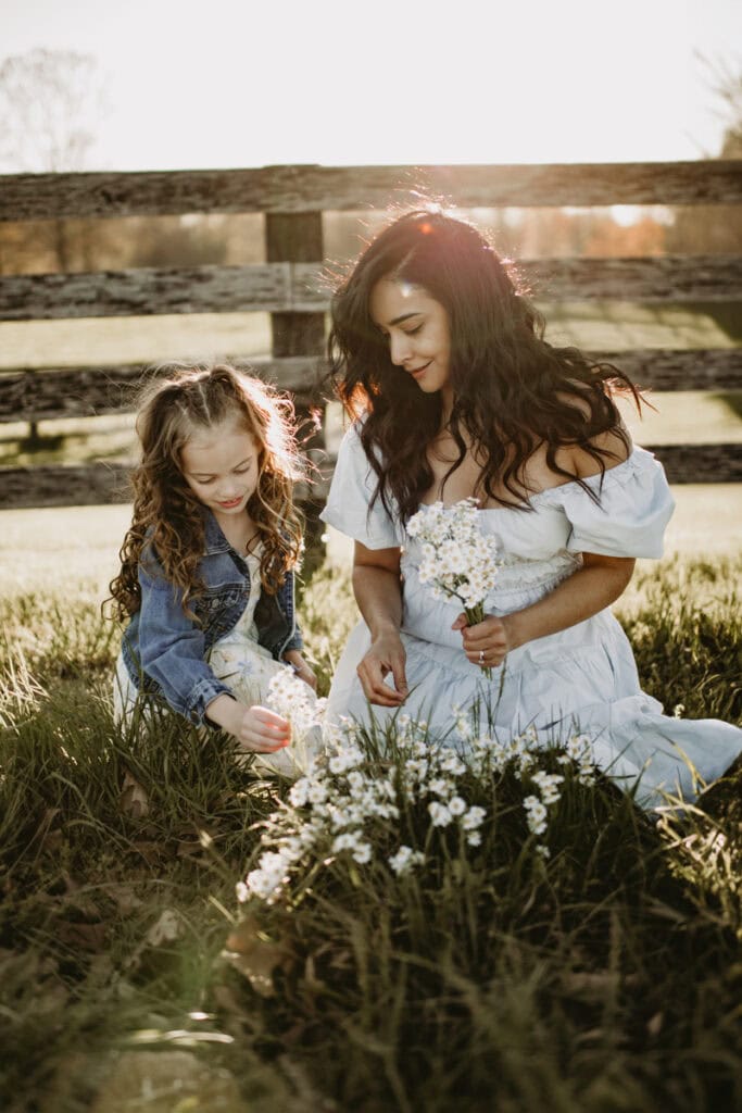 mom and daughter picking up daisies during an outside family session in loudoun county with bella luna photography, llc